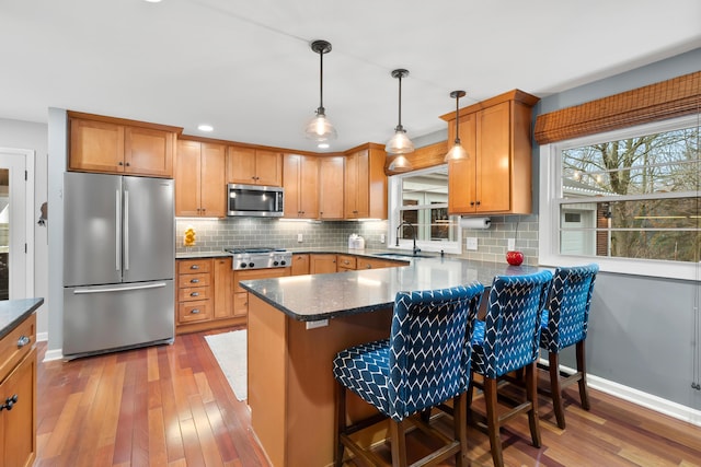 kitchen with hardwood / wood-style floors, tasteful backsplash, appliances with stainless steel finishes, and a sink