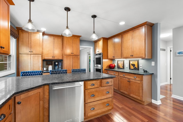 kitchen featuring visible vents, brown cabinetry, dark wood finished floors, stainless steel appliances, and pendant lighting