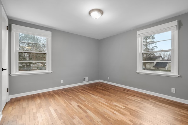 unfurnished room featuring baseboards, light wood-style floors, and a healthy amount of sunlight