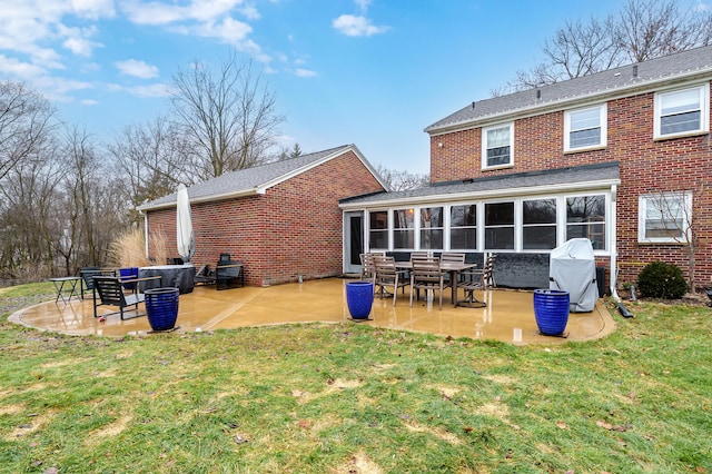 rear view of house with brick siding, a yard, a sunroom, and a patio