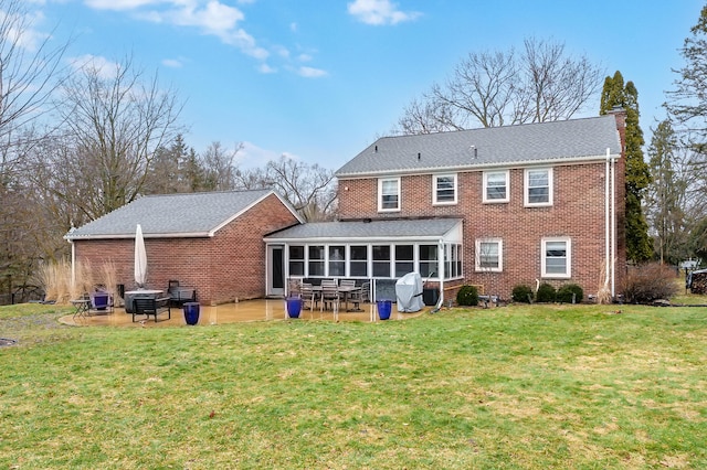 rear view of property with a lawn, brick siding, a chimney, and a sunroom