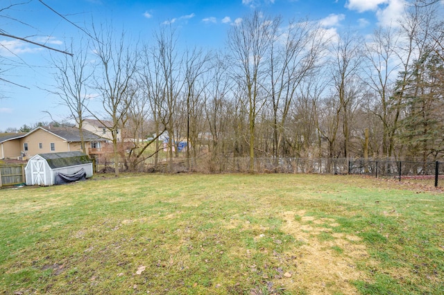 view of yard with an outdoor structure, fence, and a shed