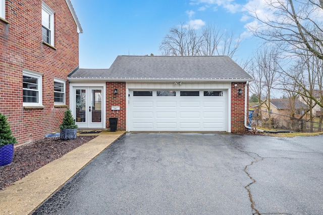 view of front facade featuring french doors, roof with shingles, an attached garage, and brick siding