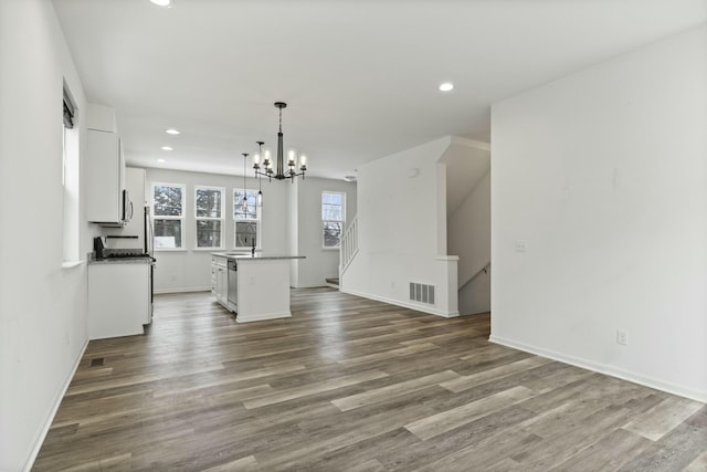 unfurnished living room with hardwood / wood-style floors and a notable chandelier