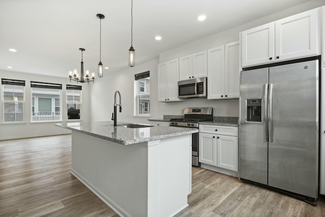 kitchen with white cabinetry, stainless steel appliances, sink, and a center island with sink