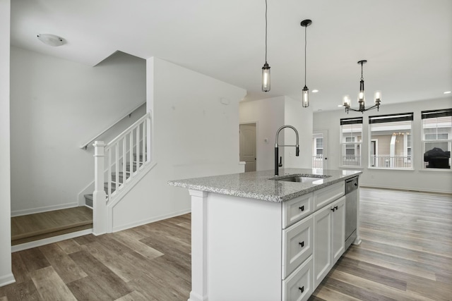 kitchen with sink, white cabinets, a kitchen island with sink, stainless steel dishwasher, and light stone counters