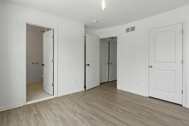 unfurnished bedroom featuring light hardwood / wood-style floors and ensuite bathroom