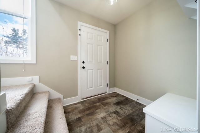 foyer with stairs, dark wood-style flooring, and baseboards