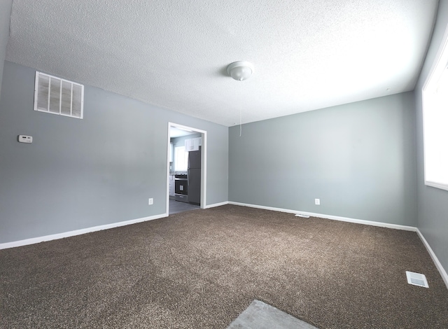 carpeted spare room with a textured ceiling