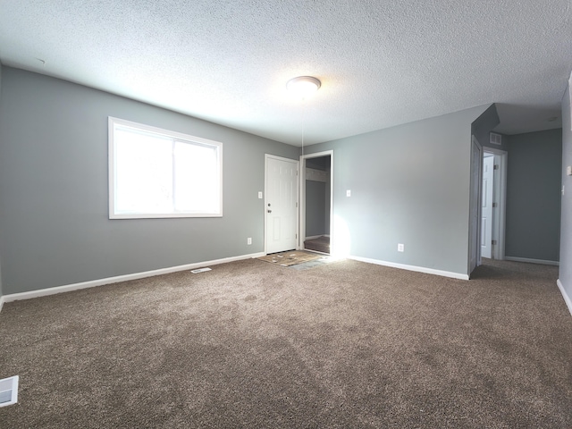 spare room with dark colored carpet and a textured ceiling