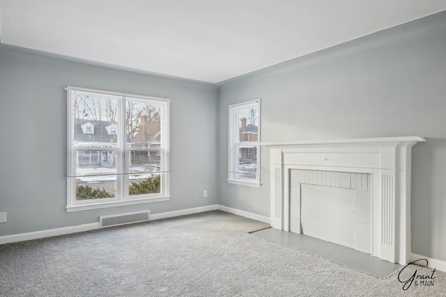 unfurnished living room with carpet floors, a fireplace, visible vents, and a wealth of natural light