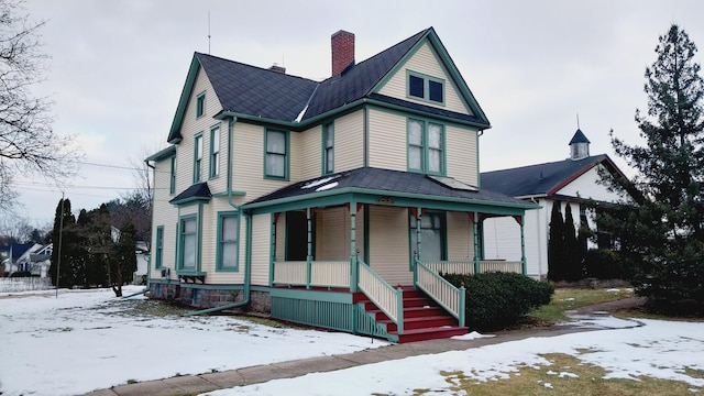 victorian home featuring a porch and a chimney