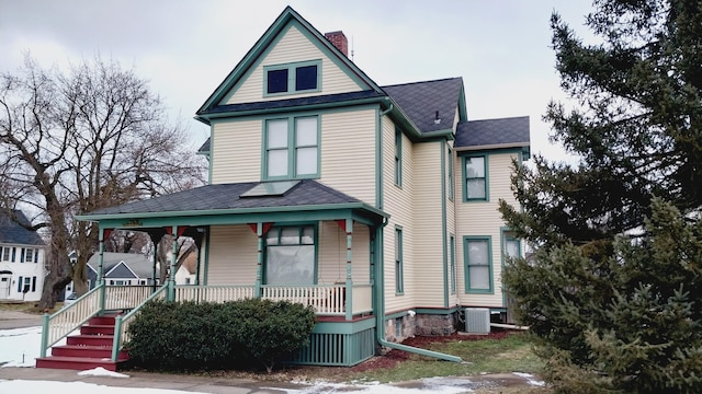 victorian-style house featuring covered porch, a chimney, and cooling unit