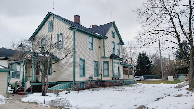 view of snow covered exterior featuring a chimney