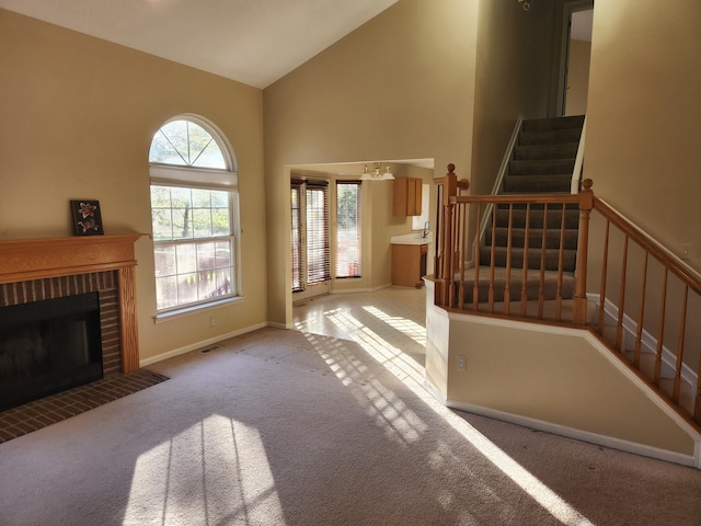 carpeted foyer with a fireplace and high vaulted ceiling