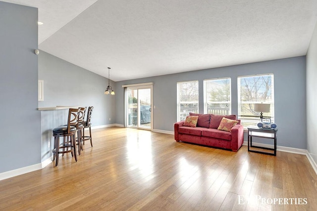 living area with baseboards, lofted ceiling, and light wood-style flooring