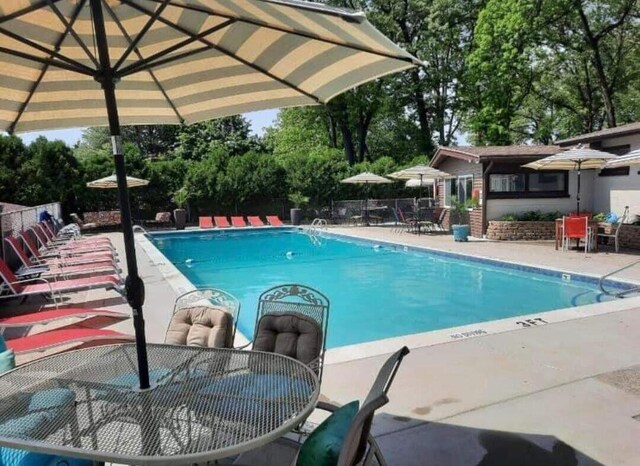 community pool featuring outdoor dining space, fence, and a patio