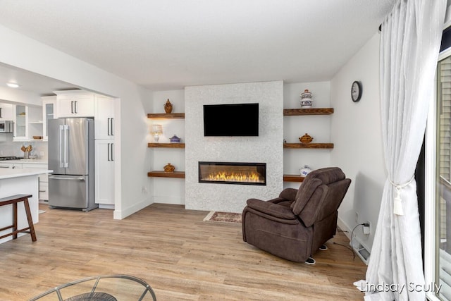 living room featuring a fireplace, light wood-type flooring, and baseboards
