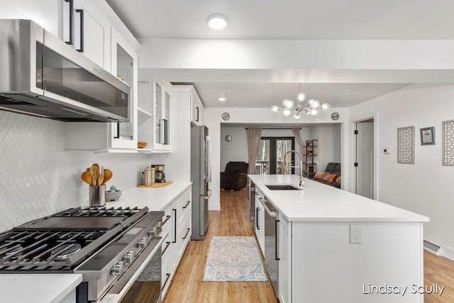 kitchen with a sink, light countertops, light wood-type flooring, and stainless steel appliances