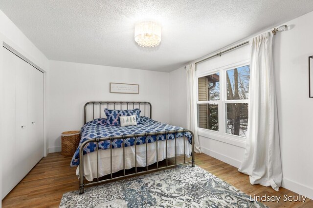 bedroom with a textured ceiling, baseboards, and wood finished floors