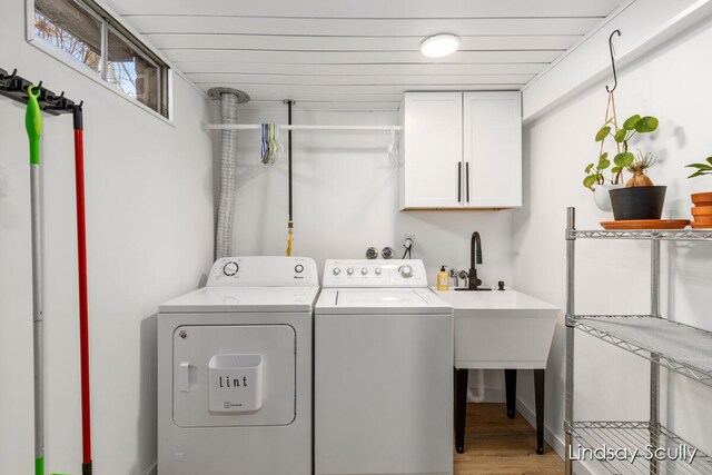 laundry area with cabinet space, washing machine and clothes dryer, and light wood finished floors