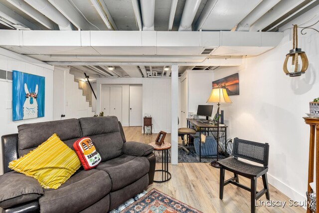 living area with wood finished floors, baseboards, visible vents, and stairway