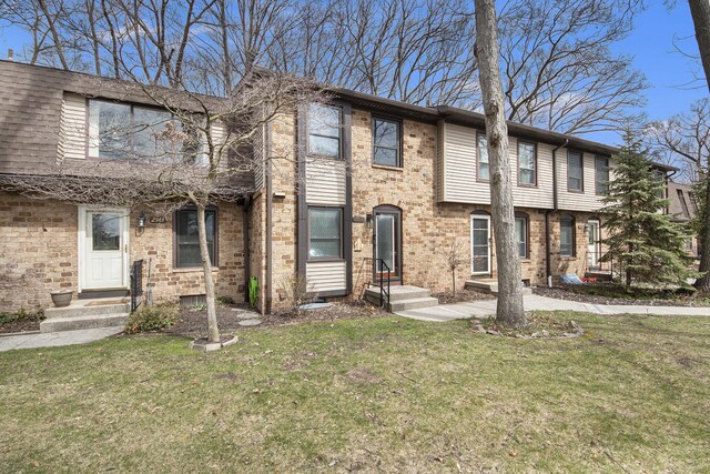 multi unit property with a front yard and brick siding