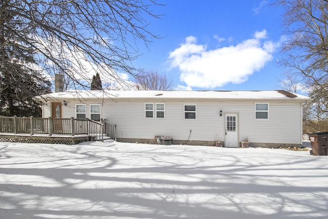 snow covered back of property with a wooden deck