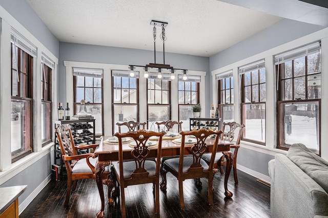 dining space featuring a textured ceiling, dark hardwood / wood-style flooring, and a healthy amount of sunlight