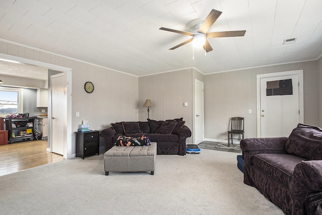 living area featuring light carpet, ceiling fan, visible vents, and crown molding