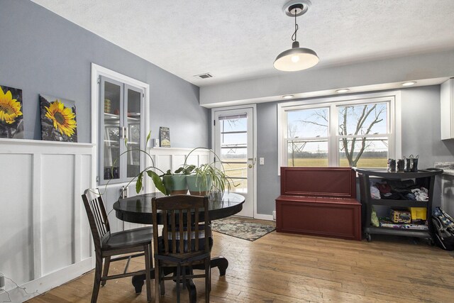 dining area featuring visible vents, a textured ceiling, and hardwood / wood-style floors