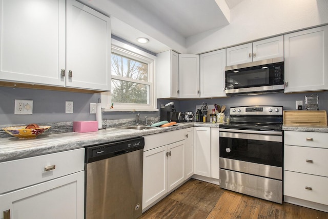 kitchen with stainless steel appliances, white cabinetry, a sink, and dark wood-style floors