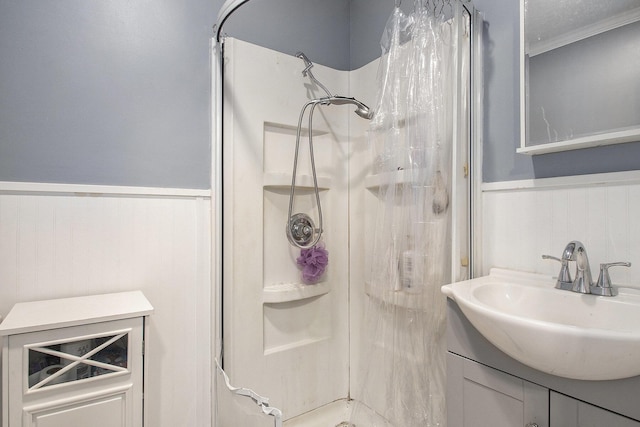 full bath featuring a wainscoted wall, vanity, crown molding, and a stall shower