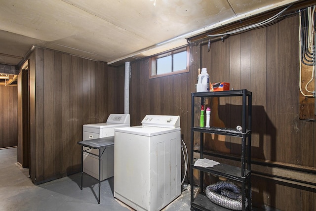 clothes washing area with laundry area, separate washer and dryer, and wooden walls