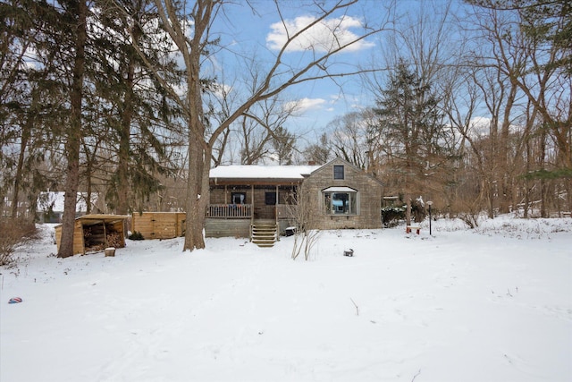 snow covered back of property featuring covered porch