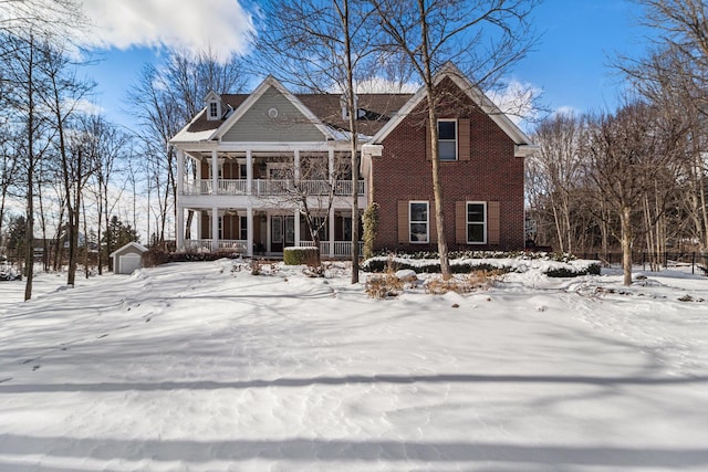 view of front of house with an outdoor structure, a porch, a balcony, brick siding, and a detached garage