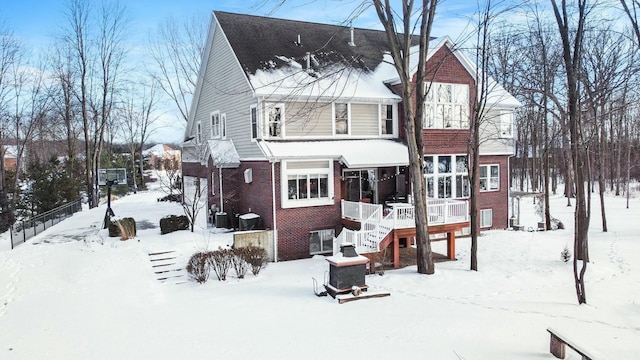 snow covered back of property featuring brick siding