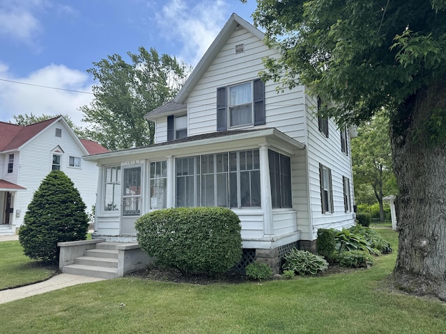 view of front facade featuring a sunroom and a front lawn