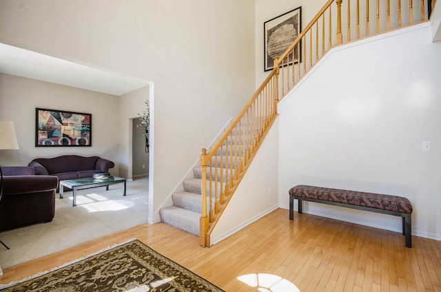 stairs with a towering ceiling, baseboards, and hardwood / wood-style flooring