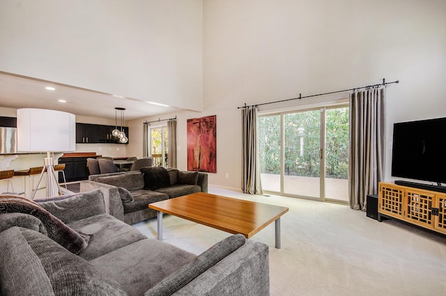 living area featuring recessed lighting, a towering ceiling, and light colored carpet