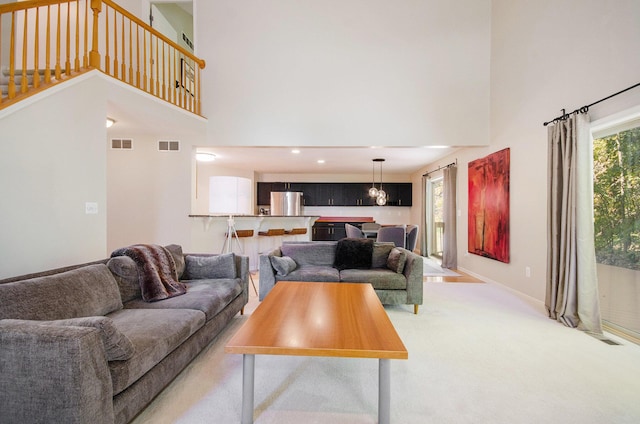 living area featuring a towering ceiling, baseboards, visible vents, and carpet flooring