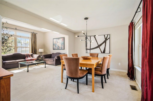 dining space featuring light carpet, visible vents, baseboards, and an inviting chandelier