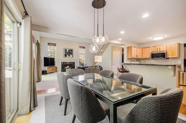 dining area featuring light wood-style floors, recessed lighting, and a premium fireplace