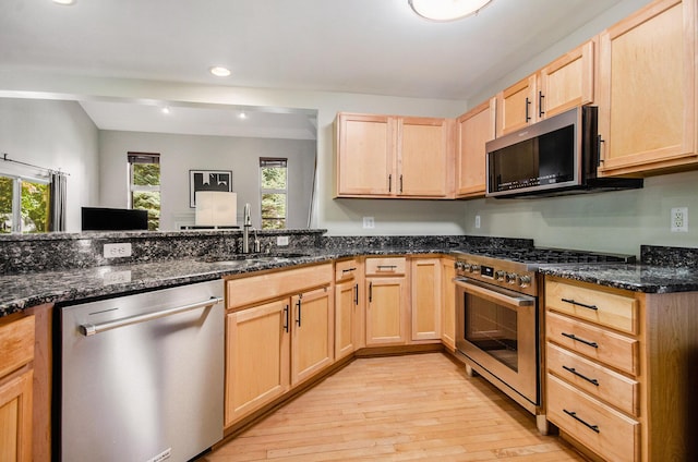 kitchen with light wood-style floors, appliances with stainless steel finishes, a sink, and light brown cabinetry