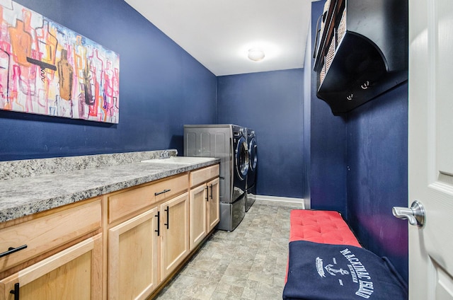 clothes washing area featuring washer and dryer, cabinet space, a sink, and baseboards