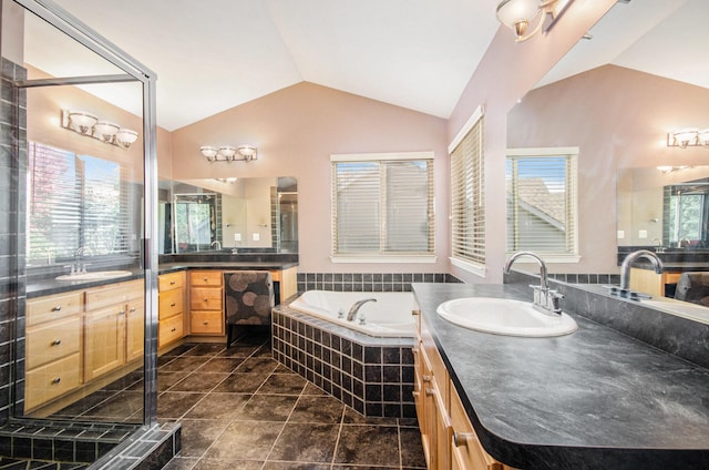 full bathroom with vaulted ceiling, two vanities, a sink, and a garden tub