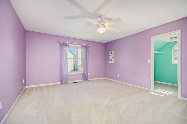 spare room featuring light carpet, ceiling fan, visible vents, and baseboards