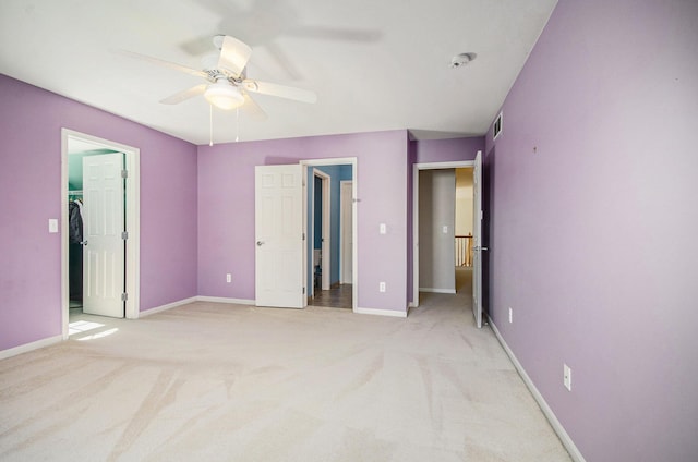 unfurnished bedroom featuring baseboards, ceiling fan, a walk in closet, and light colored carpet