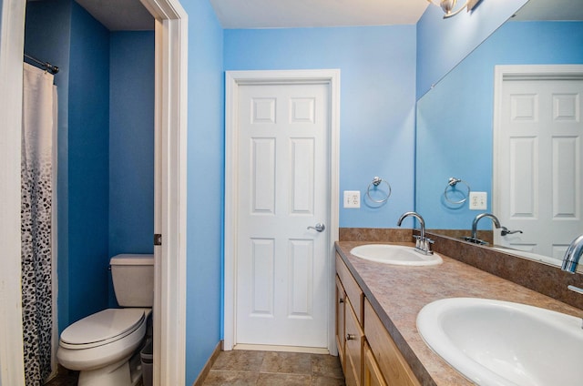 full bathroom featuring double vanity, a sink, and toilet