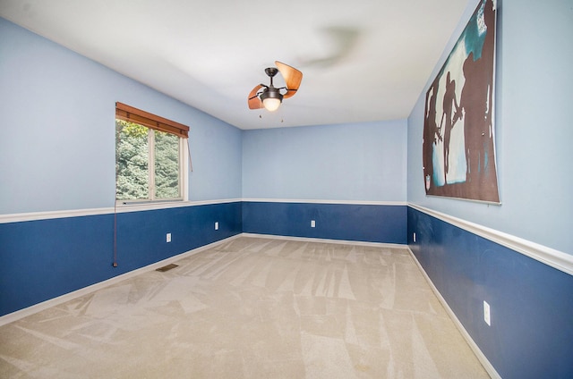 empty room with a ceiling fan, carpet flooring, visible vents, and baseboards